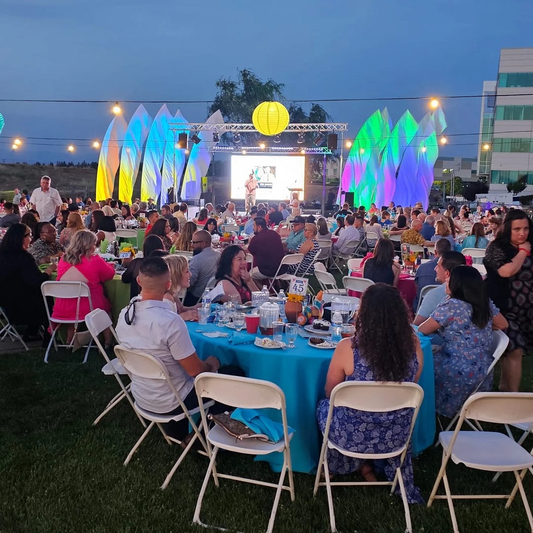 A lively corporate party at Grand on the Bluffs venue featuring attendees enjoying delicious food and drinks with a stunning view of the Palm Bluffs in the background